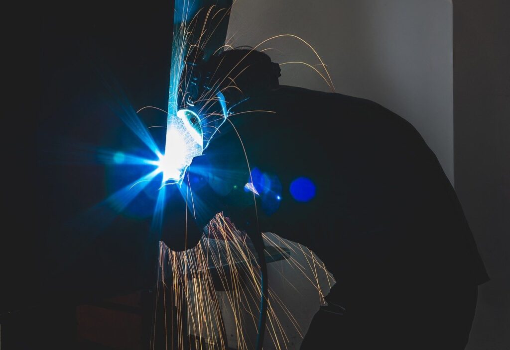 Welder working with intense sparks while welding metal, representing Welder & Fabrication recruitment opportunities.