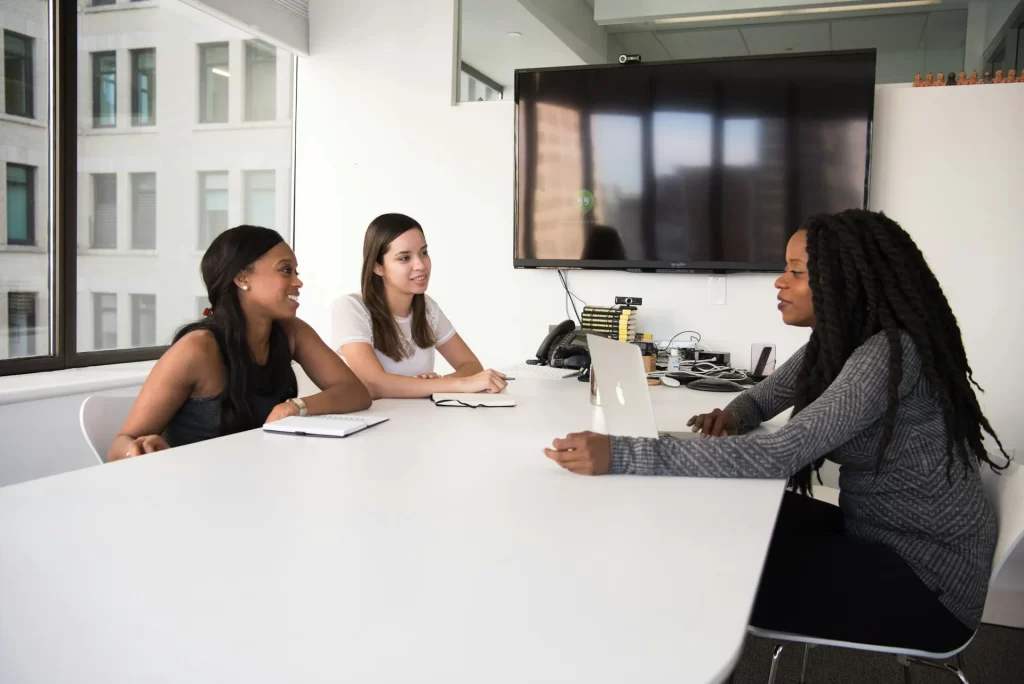 Two professional women conducting a job interview with another woman across the table in a modern office setting. The scene highlights the effectiveness of recruitment agency services in finding the right candidate.