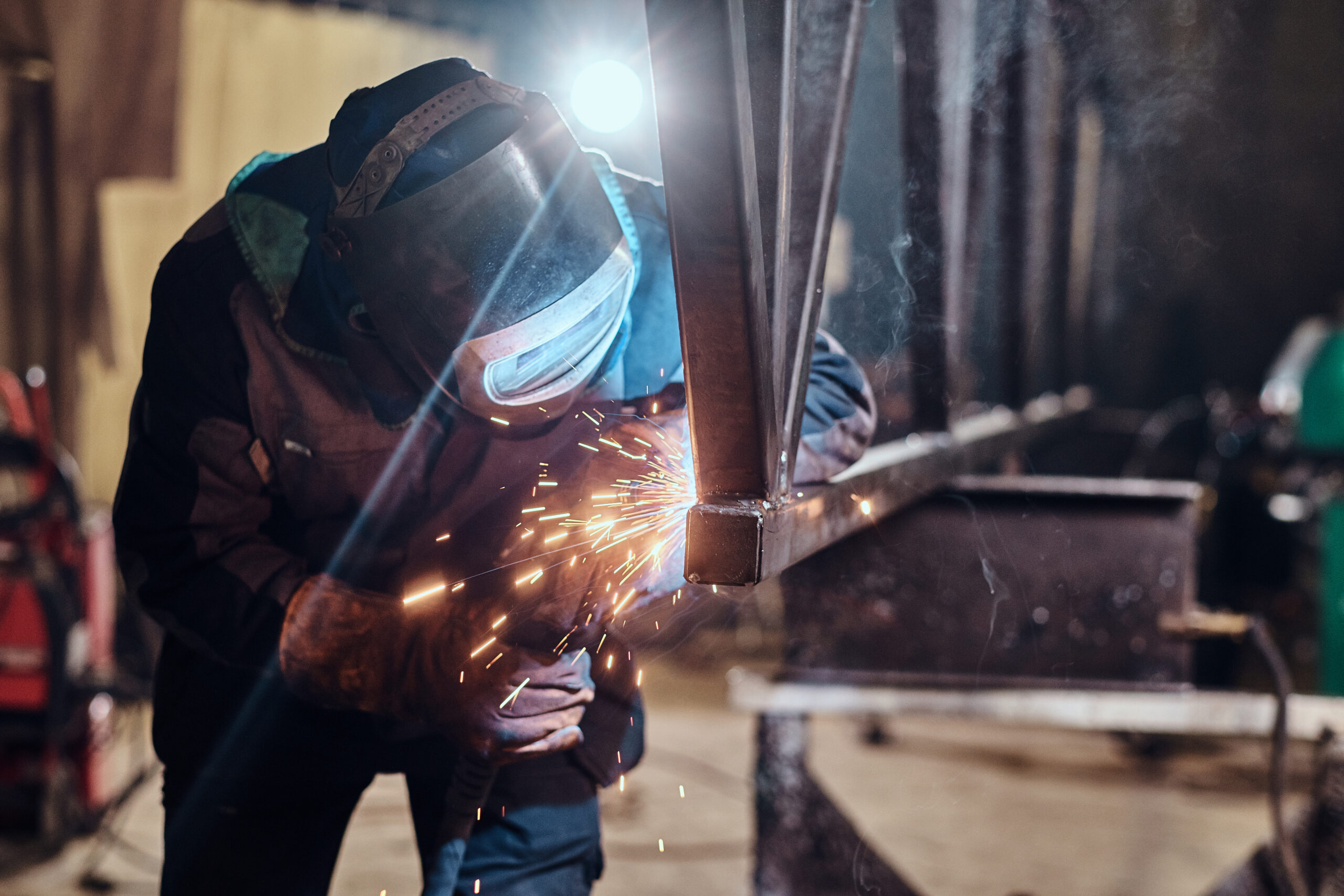 Welder working on large steel beams, showcasing the heavy-duty skills required for Welder / Fabrication jobs East Kilbride.
