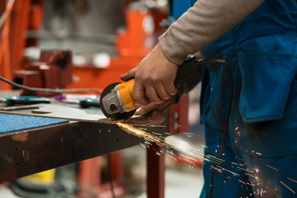 Fabricator cutting metal with a grinder, showcasing the skill and precision involved in Welder & Fabrication recruitment.