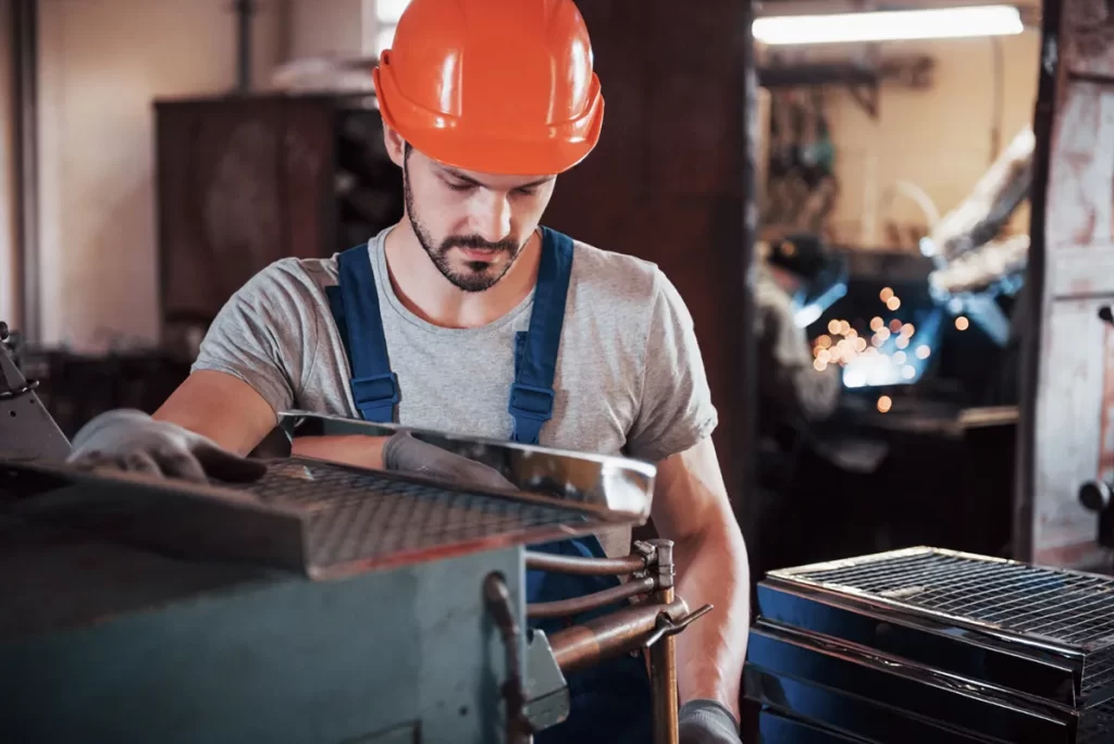 Worker operating machinery in a metalworking plant, showcasing hands-on CNC's jobs in precision manufacturing.