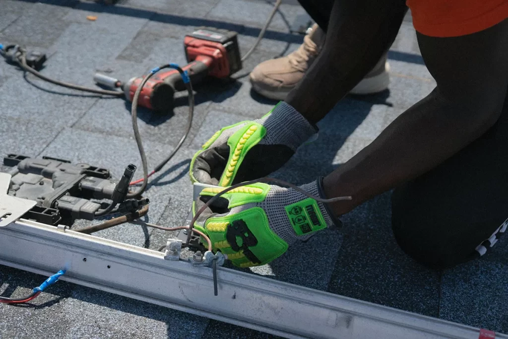 Person wearing protective gloves working with electrical wiring and components on a rooftop, representing hands-on tasks typical of Electrical Engineer Jobs East Kilbride.
