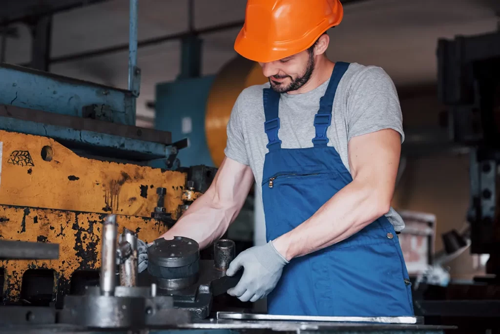 Man working on heavy machine parts positioned on a workbench, representing Mechanical Fitter Jobs Hamilton.